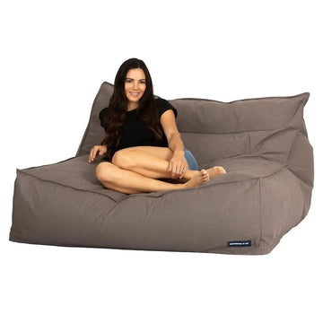 Woman sitting on a large grey bean bag chair against a white background