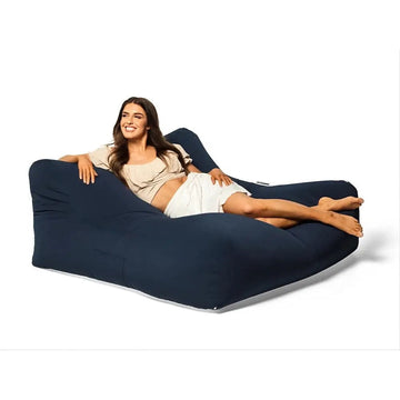 Woman lying on a navy blue bean bag chair against a white background