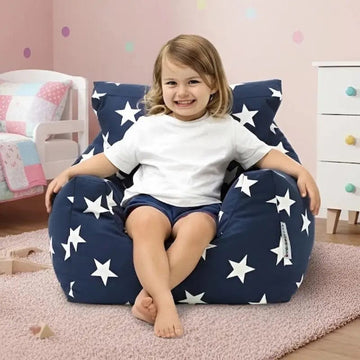 Child sitting on a navy blue bean bag chair with white star patterns in a child's room.