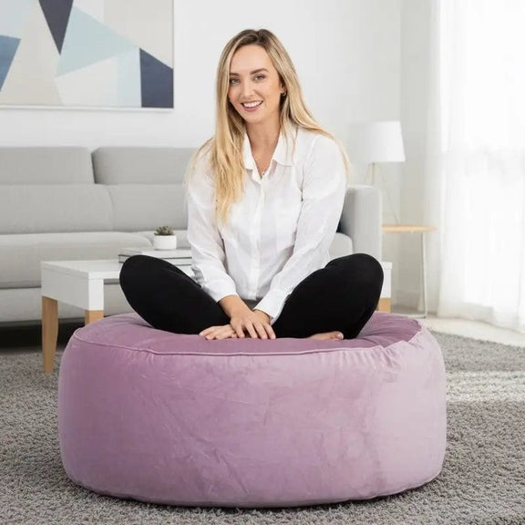 Woman sitting on a purple bean bag in a modern living room.