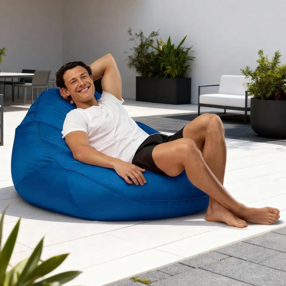 Man relaxing on a blue bean bag chair outdoors.