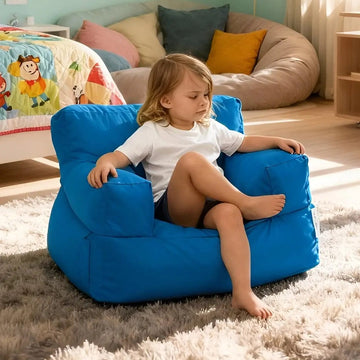 Child sitting on a blue bean bag chair in a room with colorful pillows and a bed.