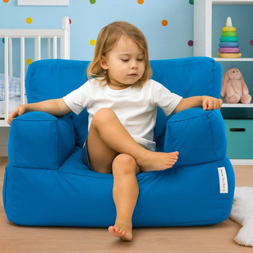 Child sitting on a blue bean bag chair in a child-friendly room with toys and furniture.
