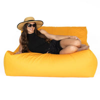 Woman lounging on an orange bean bag lounger wearing sunglasses and a wide-brimmed hat.