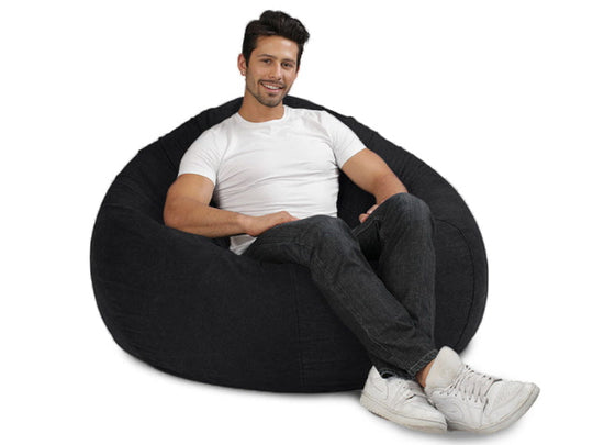 man sitting on a charcoal denim bean bag