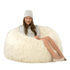 Young girl sitting on a large fluffy white bean bag chair against a white background