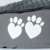 Gray pet bed with white paw prints shaped like hearts on a light gray background