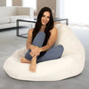 Woman sitting on a large white bean bag chair in a modern living room.