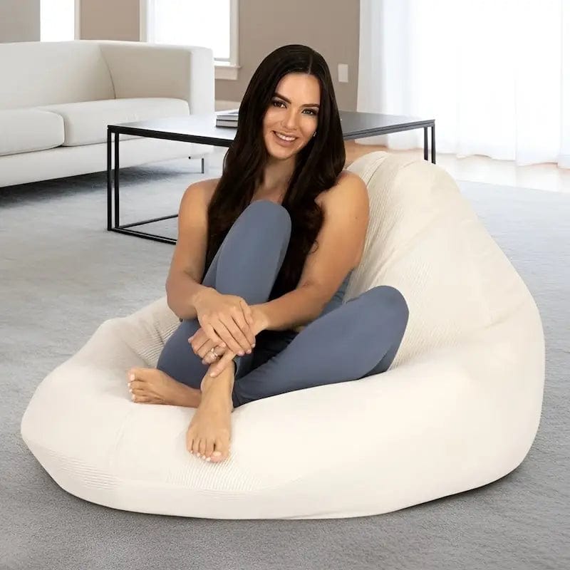 Woman sitting on a large white bean bag chair in a modern living room.
